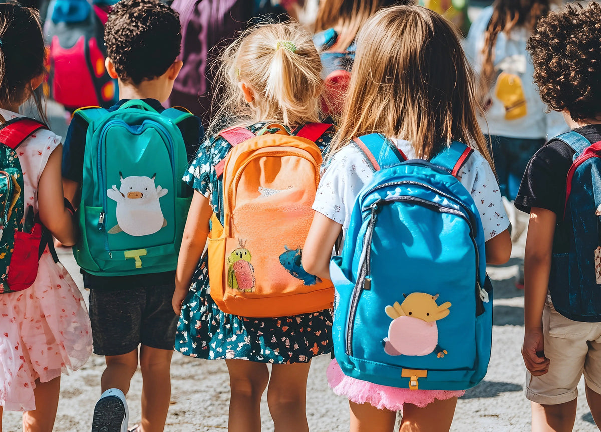 Photo de dos de trois enfants avec des cartables 